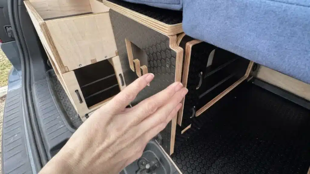 Close-up of a hand demonstrating the no-drill clamping system used to secure a Campal modular unit to the interior of a Citroën Berlingo.