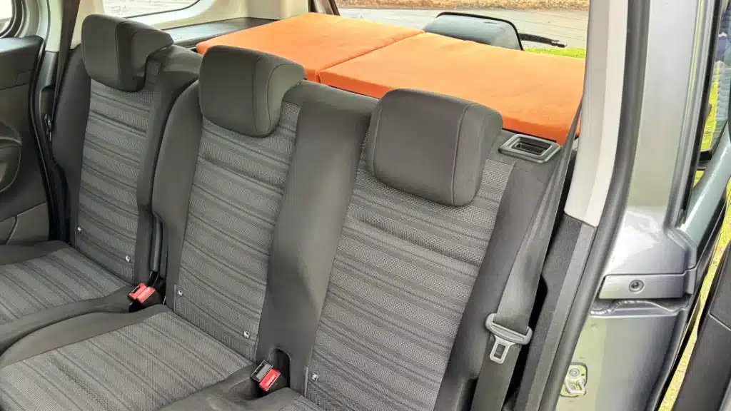 View of an orange Campal bed platform sitting behind the original 60/40 split rear seats of a Citroën Berlingo, proving it remains an everyday car.