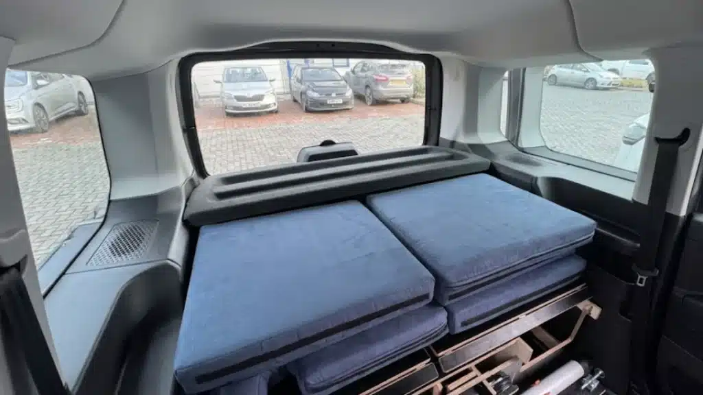 Interior view of blue 8 cm camper cushions stowed in a Citroën Berlingo, showing how the stack stays below the parcel-shelf for clear rear visibility.