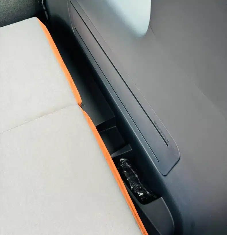 Close-up of the Campal camper bed cushion fitting seamlessly inside the Kia PV5, maintaining easy access to the factory cup holders and interior storage