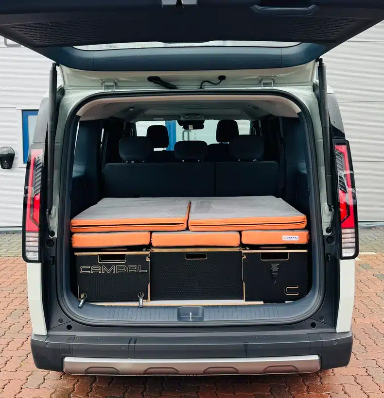 Fully removable Campal camper unit folded completely into the boot of a Kia PV5, demonstrating how 5-seat functionality is preserved for daily driving