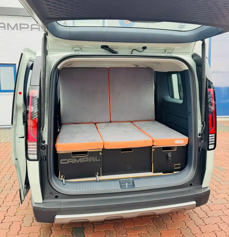 Campal conversion kit in the Kia PV5 configured into a relaxed indoor sofa layout with upright backrests for comfortable lounging