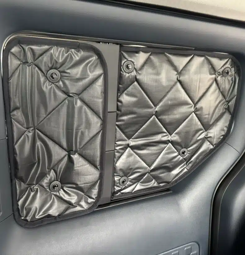 Close-up of the insulated thermal window covers installed securely on the rear side windows of the Kia PV5 electric campervan